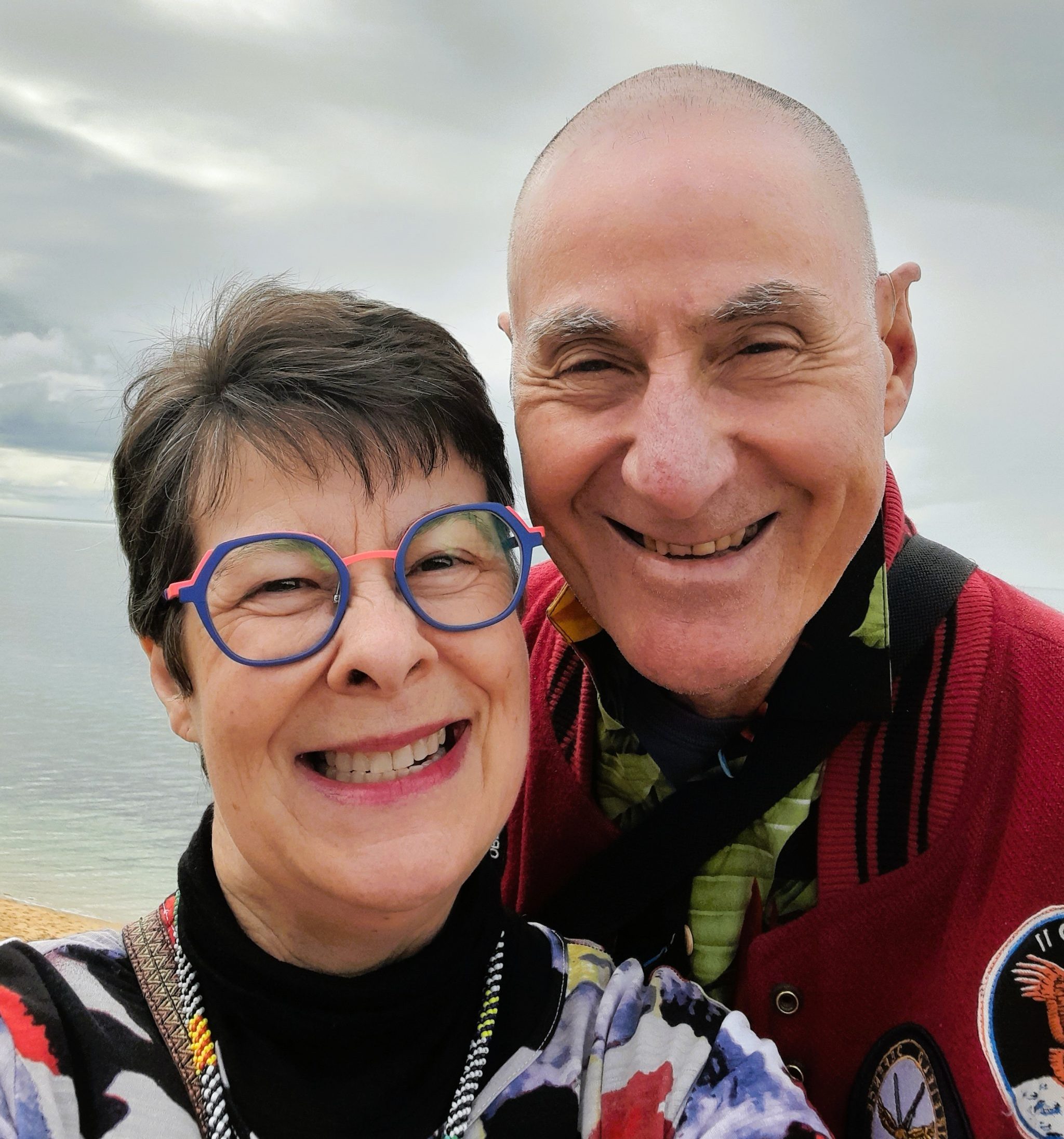 Woman and man smiling. Cloudy backdrop.