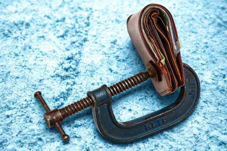 A brown wallet is being squeezed tightly inside a G clamp