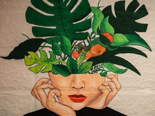 painting of woman with green leaves and orange flowers coming out of her head